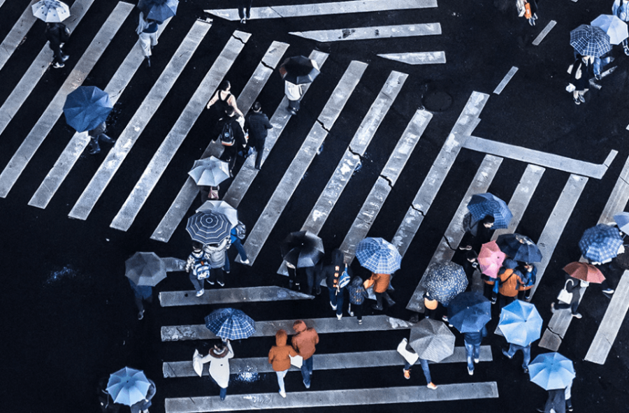 pedestrian traffic at a crosswalk with umbrellas